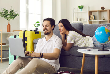 Long-awaited holidays. Couple is preparing for a vacation and is looking for online tours using a...