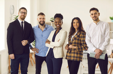 Group of five millennial people in office suits smiling and looking at camera. Portrait of...