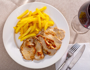 Fried pork with potatoes on a ceramic plate cooked in a restaurant