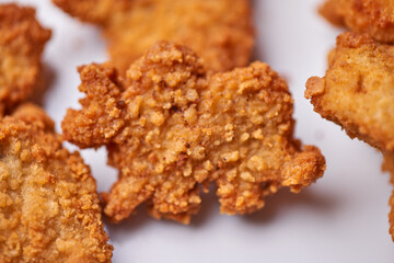 macro closeup of dinossaur shaped chicken nuggets snacks on white plate