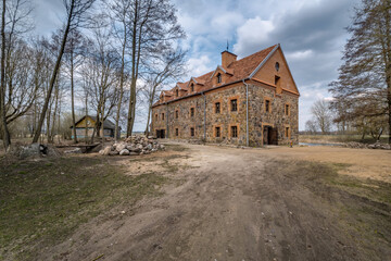 Fototapeta na wymiar the building of the restored old stone mill in early spring
