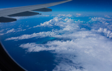 Fototapeta na wymiar aircraft wing with clouds and coast line all blue