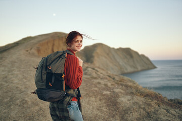 beautiful traveler by the sea in the mountains and sunset in the background cropped view