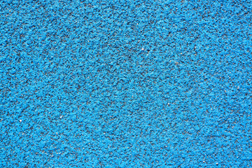 Textured blue background. Rubber, protective covering for stadiums, running tracks, tennis courts. Top view, close-up, outside