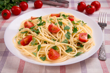 Pasta spaghetti with cherry tomatoes and parsley on a light background.