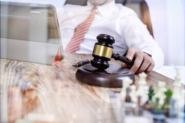 justice and law concept.Male judge in a courtroom with the gavel,working with,digital tablet computer docking keyboard,eyeglasses,on wood