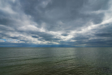 The surface of the sea under a cloudy blue sky.