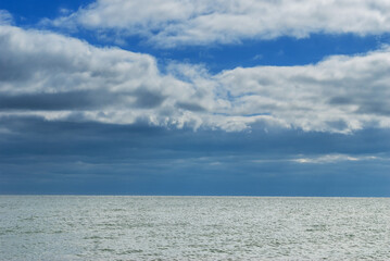 The surface of the sea under a cloudy blue sky.