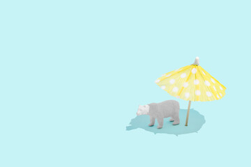 Minimal global climate change summer concept with white polar bear sunbathing under an umbrella on bright blue background. Planet Earth melting and endangered species protection idea. Copy space.