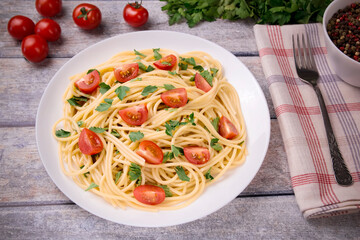 Pasta spaghetti with cherry tomatoes and parsley on a light background.