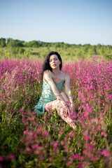 Girl in a turquoise dress in a blooming field