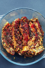 Korean style marinated pork belly slices in a glass bowl. Selective focus. Meat industry product. Top down view.