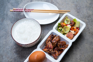 Thai rice gruel eating with side dish crispy squid, boiled egg and spicy sausage salad