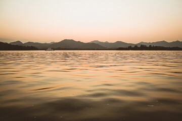 Panorama scenery of Morning fall nature misty foggy scene: forest with trees surrounded by  mist on the water surface of lake with hills and 
Leifeng Pagoda of West lake Hangzhou in the background.
