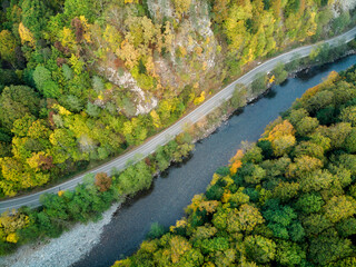 Aerial view of the road and colorful autumn forest with a mountain river in Russia, Adygea