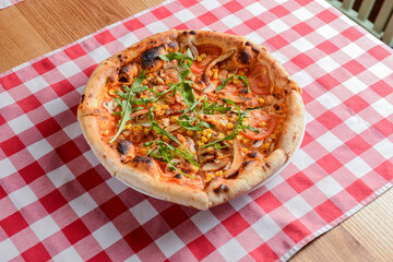 Delicious italian pizzas served on wooden table with red plaid table cloth.