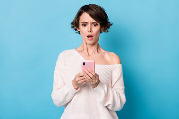 Photo portrait of upset girl holding phone in two hands isolated on pastel blue colored background