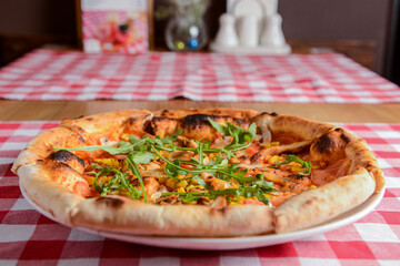 Delicious italian pizzas served on wooden table with red plaid table cloth.