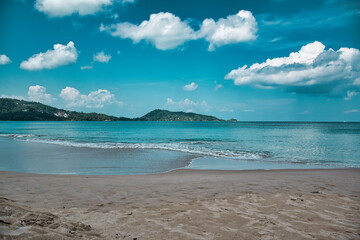 Fototapeta na wymiar Empty, calm sandy crescent Patong Beach with turquoise blue clear water and cirrus cloudy sky