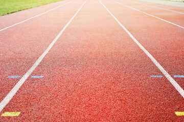 Fototapeta premium Empty street stadium on a sunny morning. Red rubberized treadmills, white line markings. Sport, active lifestyle concept