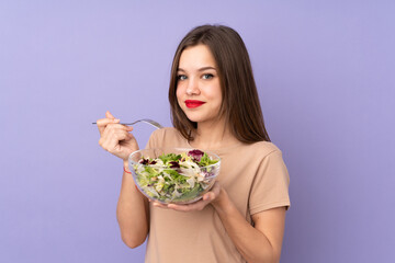 Teenager girl holding salad isolated on purple background