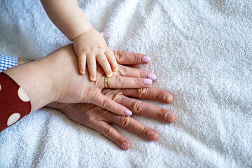 three hands against a white sheet. mom, dad, baby. family strength and love.