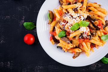 Pasta penne with eggplant. Pasta alla norma - traditional Italian food with eggplant, tomato, ricotta cheese and basil. Top view, overhead, copy space
