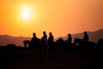 Silhouette Cowboy on horseback against a beautiful sunset, cowboy and horse at first light,mountain, river and lifestyle with natural light background..
