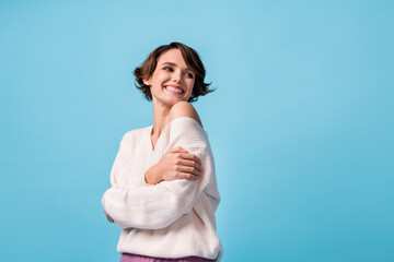 Photo of young girl happy positive smile dream look empty space hug cuddle herself comfort cozy isolated over blue color background