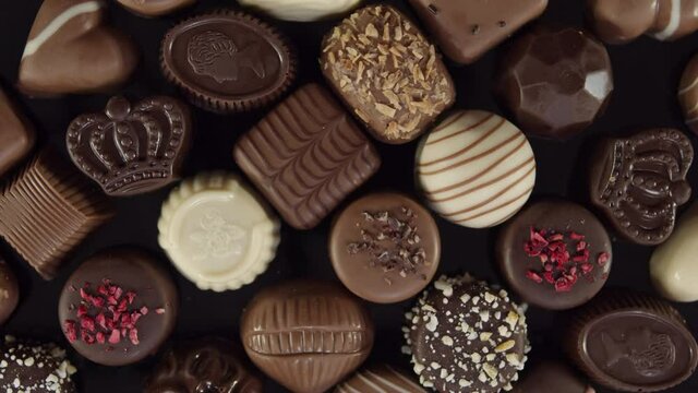 Bonbon chocolates pralines rotating, decorative sweets spinning, valentines holiday gift. Close up overhead top view.
