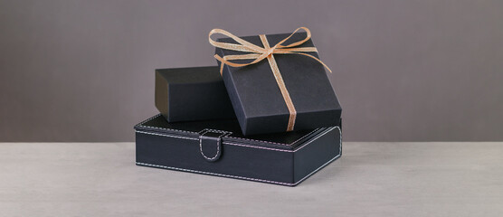 Back gift box. Golden ribbon on gift on a grey background. Copy space