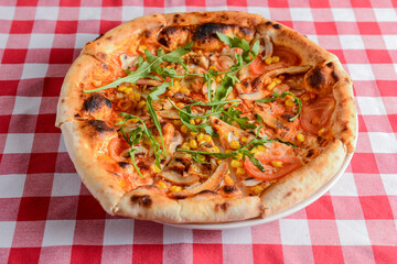 Delicious italian pizzas served on wooden table with red plaid table cloth.