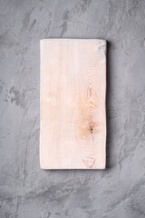 Handcrafted white old wooden cutting board on stone concrete background, top view