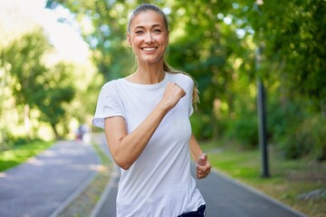 Woman running asphalt road summer park