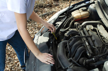 Fototapeta na wymiar the girl checks the oil under the hood of the car
