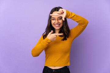 Young mixed race woman isolated on purple background focusing face. Framing symbol