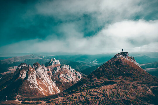 Man standing on top of cliff in summer mountains