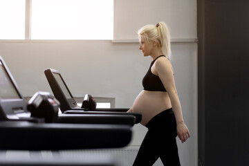 Pregnant Woman training treadmill machine in gym Cardio exercises on Running simulator