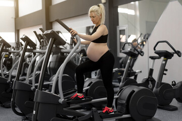 Fototapeta na wymiar Pregnant Woman training pregnancy elliptical trainer in gym Cardio exercises on Running simulator