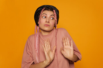Portrait of fashionable European girl in oversized pinkish tee posing isolated making emotional gesture with hands, saying No, rejecting something, feeling uncomfortable. Personal boundaries