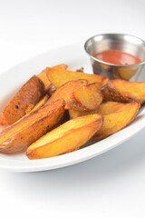 Roasted or baked potatoes with rosemary in a white bowl. Potatoes in rural style served with sauce.