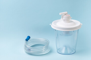 Plastic canister from medical suction machine on blue. Part of portable aspirator used to remove...