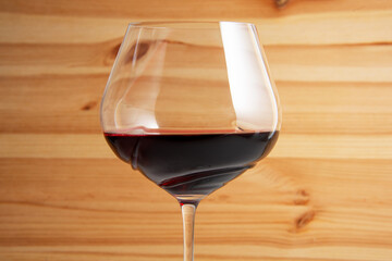 Elegant wineglass with red wine on bright vintage wooden background
