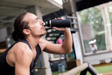 young athlete drinking water while resting