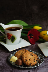 one white cup of tea and yellow and red tulips