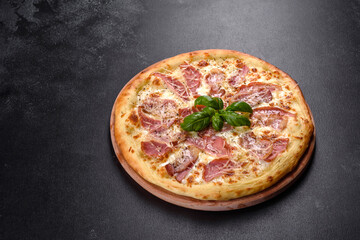 Delicious fresh crispy pizza from the oven with ham, cheese and basil