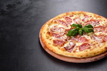 Delicious fresh crispy pizza from the oven with ham, cheese and basil