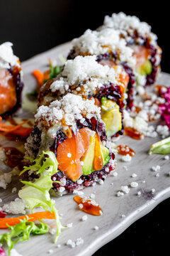 Japanese sushi with black rice and prawns. Vertical image. Dark food