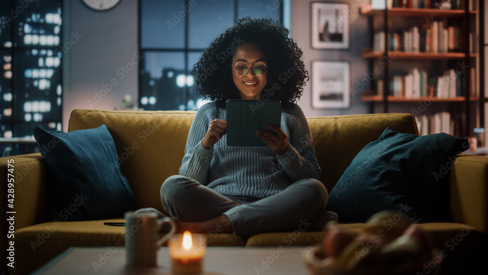 Aufkleber beautiful authentic latina female sitting on couch sofa in a cozy dark living room in the evening an