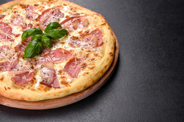 Delicious fresh crispy pizza from the oven with ham, cheese and basil